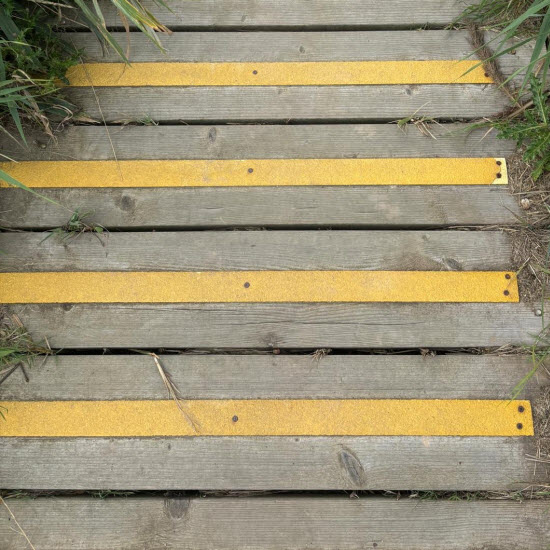 Yellow fibreglass anti-slip strips fixed across timber decking, with exposed boards between them
